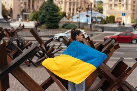 Junge Frau mit Nationalflagge der Ukraine läuft durch die Stadt