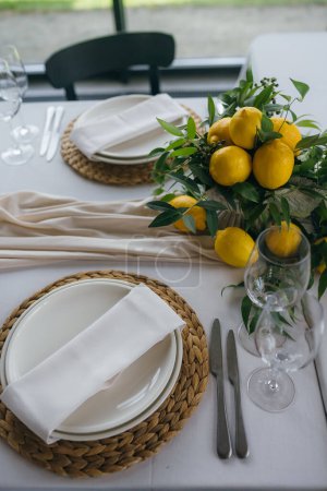 Photo for Festive table at the wedding party are decorated with lemon arrangements, on the table are plates with napkins and glasses - Royalty Free Image