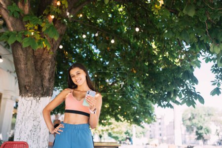 Téléchargez les photos : Photo de charmante jolie jeune femme communiquant gadget moderne souriant à l'extérieur de la rue urbaine de la ville - en image libre de droit