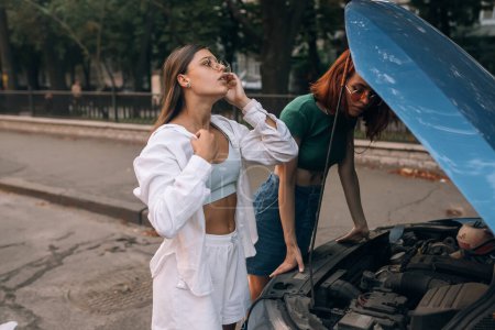 Photo for Women with broken down car on the road. Look for someone help. - Royalty Free Image