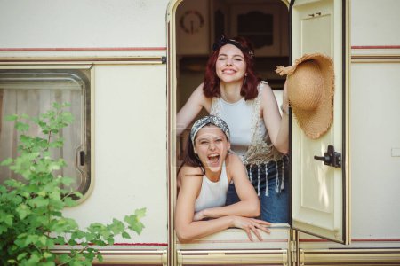 Happy hippie friends are having a good time together in camper trailer. Holiday, vacation, trip concept. High quality photo