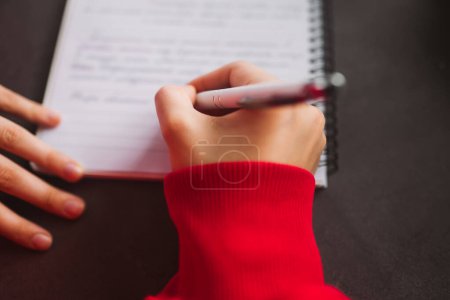 Foto de Vista superior Close-up womans mano sosteniendo un lápiz y escribiendo información en un cuaderno. Foto de alta calidad - Imagen libre de derechos