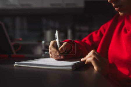 Photo for Close-up womans hand holding a pencil and writing information in a notebook. High quality photo - Royalty Free Image