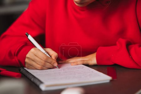 Téléchargez les photos : Gros plan femmes main tenant un crayon et d'écrire des informations dans un carnet. Photo de haute qualité - en image libre de droit
