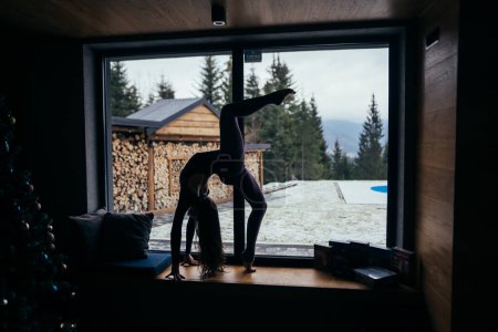 Téléchargez les photos : Belle fille fait des exercices de yoga à la maison étirant le corps à la maison sur le sol concentré sur la pratique. Jeunes, intérieurs et mode de vie sain concept. - en image libre de droit