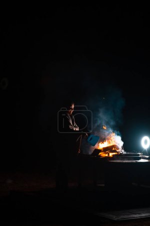 Photo for Man preparing bbq grill to cook on fire. Outside dark shot. Freeze moment of fire. High quality photo - Royalty Free Image