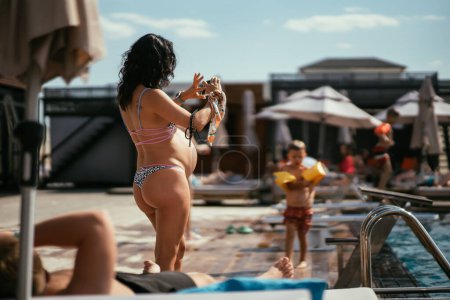 Téléchargez les photos : Vue arrière de la femme enceinte en bikini sur la plage. Photo de haute qualité - en image libre de droit