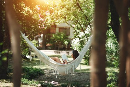 Photo for Happy hippie girl is reading a book in hammock having a good time with playing in camper trailer. Holiday, vacation, trip concept.High quality photo - Royalty Free Image