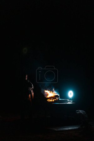 Téléchargez les photos : Homme préparant barbecue grill à cuire sur le feu. Tir à l'extérieur. Geler le moment du feu. Photo de haute qualité - en image libre de droit