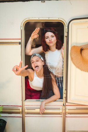 Glückliche Hippie-Freunde amüsieren sich gemeinsam in einem Wohnwagen. Urlaub, Urlaub, Reisekonzept. Hochwertiges Foto