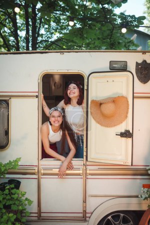 Photo for Happy hippie friends are having a good time together in a camper trailer. Holiday, vacation, trip concept. High quality photo - Royalty Free Image