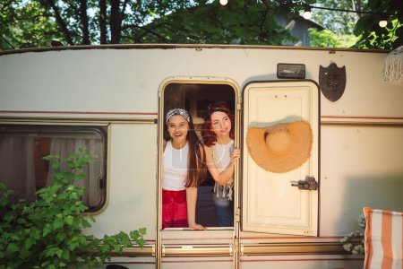 Téléchargez les photos : Heureux amis hippies passent un bon moment ensemble dans une caravane de camping-car. Vacances, vacances, concept de voyage. Photo de haute qualité - en image libre de droit