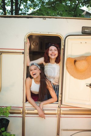 Téléchargez les photos : Heureux amis hippies passent un bon moment ensemble dans une caravane de camping-car. Vacances, vacances, concept de voyage. Photo de haute qualité - en image libre de droit