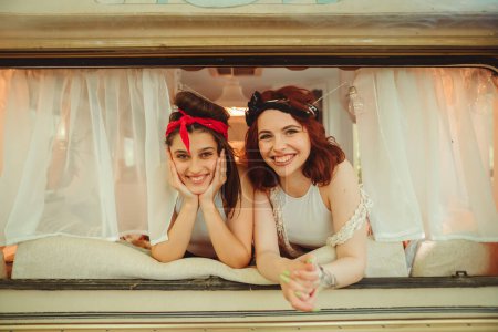 Photo for Happy hippie friends are having a good time together in a camper trailer. Holiday, vacation, trip concept. High quality photo - Royalty Free Image