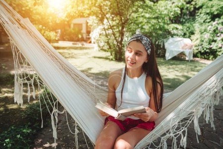 Photo for Happy hippie girl is reading a book in hammock having a good time with playing in camper trailer. Holiday, vacation, trip concept.High quality photo - Royalty Free Image