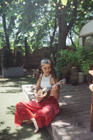 Téléchargez les photos : Bonne fille hippie passent un bon moment avec jouer à la guitare dans la bande-annonce du camping-car. Vacances, vacances, concept de voyage. Photo de haute qualité - en image libre de droit