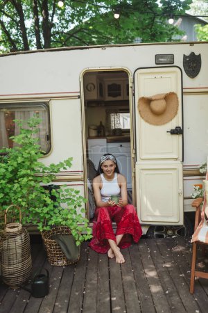 Foto de Chica hippie feliz se están divirtiendo con la taza de té en caravana remolque. Vacaciones, vacaciones, concepto de viaje.Foto de alta calidad - Imagen libre de derechos