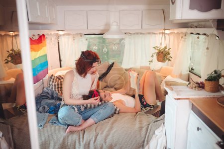 Téléchargez les photos : Portrait d'un couple lesbien mignon. Deux filles passent du temps ensemble dans une caravane avec un drapeau LGBT sur le mur. Amour et attitude. Concept LGBT. Photo de haute qualité - en image libre de droit