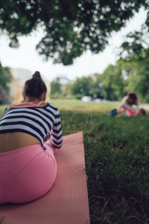 Téléchargez les photos : Une vue de derrière la fille pendant la séance de yoga dans le parc. Photo de haute qualité - en image libre de droit