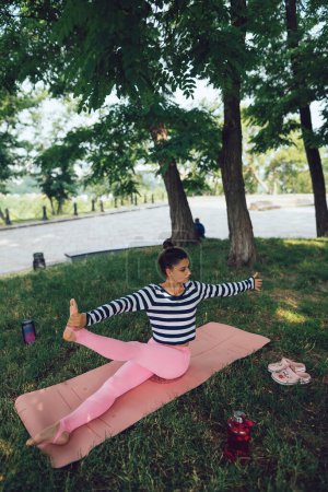 Téléchargez les photos : Jambes tendues lors d'une séance de yoga dans le parc. Photo de haute qualité - en image libre de droit