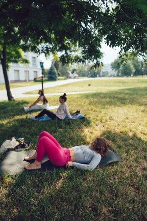 Téléchargez les photos : La fille est à une séance de yoga de groupe dans le parc. Photo de haute qualité - en image libre de droit