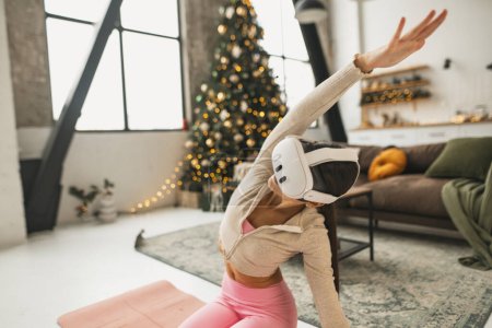 Téléchargez les photos : Organiser des cours d'entraînement en ligne à la maison avec un casque de réalité virtuelle pendant la période des fêtes de Noël. Photo de haute qualité - en image libre de droit
