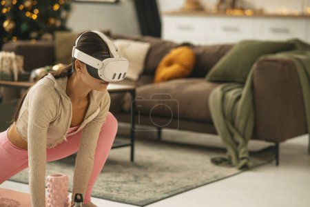 Foto de Una dama joven agraciada con atuendo atlético estirándose mientras usa un auricular de realidad virtual. Foto de alta calidad - Imagen libre de derechos