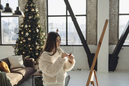 Photo for Radiating happiness, a vibrant young lady wearing a Christmas reindeer mask beams in the apartment. High quality photo - Royalty Free Image