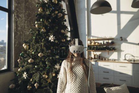 Téléchargez les photos : Dans la lueur d'une matinée d'hiver, une jeune femme brillante explore la réalité virtuelle avec un casque. Photo de haute qualité - en image libre de droit