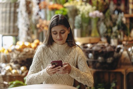 Photo for In the decor store, a beautiful young woman is seen with her phone. High quality photo - Royalty Free Image
