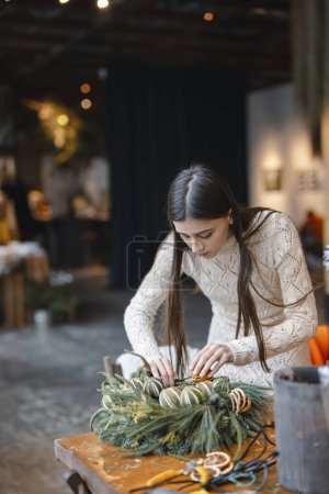 Téléchargez les photos : La couronne de Noël, prête à être exposée, est finalisée au comptoir de la boutique de fleurs. Photo de haute qualité - en image libre de droit