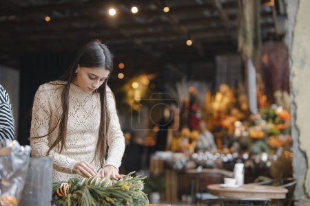 Téléchargez les photos : Finition de la couronne de Noël exposée au comptoir de la boutique de fleurs. Photo de haute qualité - en image libre de droit