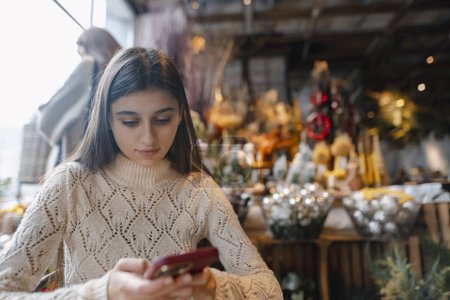 Photo for A beautiful young woman holds her phone while browsing the decor store. High quality photo - Royalty Free Image