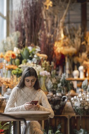 Foto de Una hermosa dama usa su teléfono mientras hace compras en la tienda de decoración. Foto de alta calidad - Imagen libre de derechos