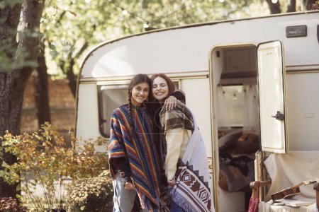 Téléchargez les photos : Deux dames chics adoptent la mode hippie avec une bande-annonce comme toile de fond. Photo de haute qualité - en image libre de droit