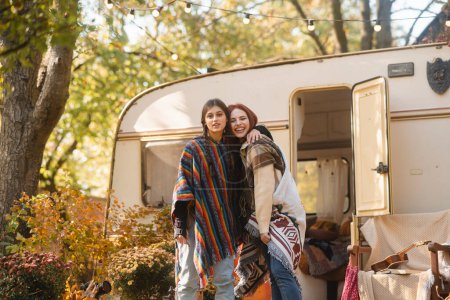 Photo for Two stylish girls in hippie attire pose against the backdrop of a trailer. High quality photo - Royalty Free Image