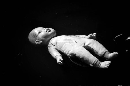 Foto de Una fotografía en blanco y negro de una muñeca abandonada flotando en un estanque - Imagen libre de derechos
