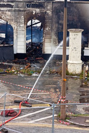 Photo for An unmanned hose damps down the remains of the Royal Pier Hotel in Weston-super-Mare, UK on 30 September 2010 after it had been badly damaged by the second fire in less than 18 months. - Royalty Free Image