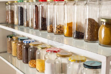 Foto de Vista lateral de algunos recipientes de vidrio con comida a granel en un estante de pared. Reutilización de envases de vidrio para productos industrializados. - Imagen libre de derechos