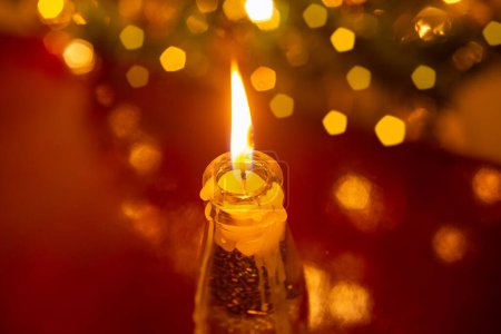 Photo for Christmas decoration. A burning candle over and defocused Christmas tree detail reflected in the surface. - Royalty Free Image