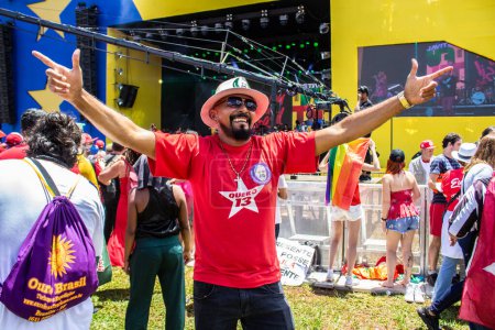 Téléchargez les photos : Un homme heureux à bras ouverts et un T-shirt avec le symbole PT. Photo prise lors de l'inauguration du nouveau président du Brésil. - en image libre de droit