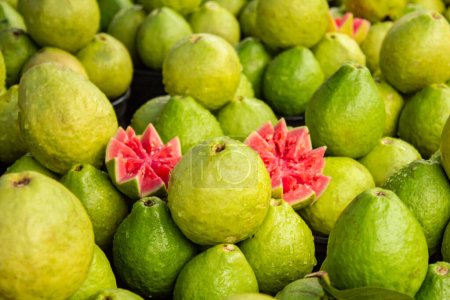Various guavas on display with some cut and arranged to be sold at a fair.