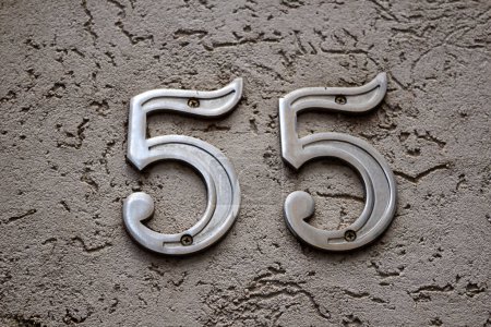 Foto de Number fifty-five in metal nailed to the wall of a building. 55. - Imagen libre de derechos