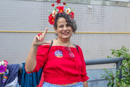 Foto de Una mujer, vestida con ropa roja y haciendo la "L" de Lula. Foto tomada durante el acto de inauguración del Presidente de Brasil. - Imagen libre de derechos