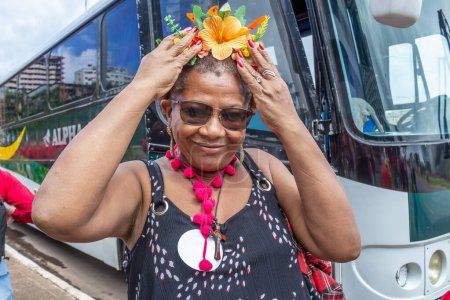 Foto de Una mujer de mediana edad, sonriendo, coloca una tiara con flores en la cabeza. Foto tomada durante el acto de inauguración del Presidente de Brasil. - Imagen libre de derechos