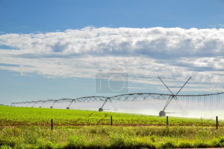 Photo for Irrigation machine watering the growing crop, on a clear day with some clouds in the sky. - Royalty Free Image