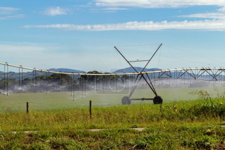 Photo for Detail of an irrigation machine watering the growing crop, on a clear day with some clouds in the sky. - Royalty Free Image