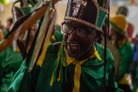 Foto de Primer plano de una persona vestida con ropa verde y sombrero, durante Congadas, un festival religioso con elementos de tradiciones tribales de Angola y Congo. - Imagen libre de derechos