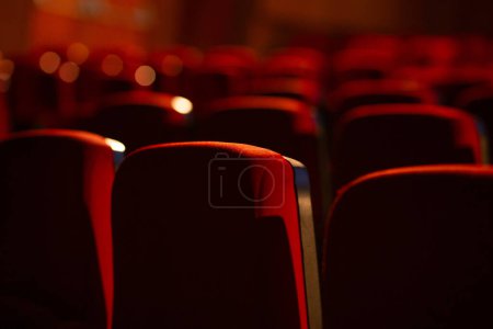 Foto de Detalle de un teatro vacío. Varias filas de sillones rojos fotografiados desde atrás. Fotografía con enfoque estrecho. - Imagen libre de derechos