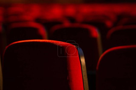Foto de Detalle de un teatro vacío. Varias filas de sillones rojos fotografiados desde atrás. Fotografía con enfoque estrecho. - Imagen libre de derechos